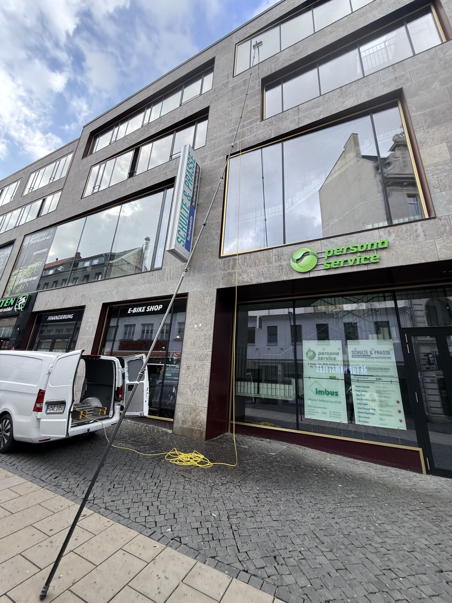 Glas-Fassadenreinigung Reinigung der Fensterscheiben von außen mithilfe eines sehr langen Putzgerätes